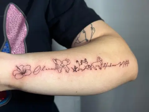 Hibiscus, lettering, and small figures along the forearm — Ohana and Hakuna Matata.
